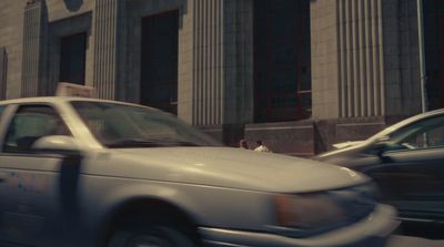 a white car driving down a street next to tall buildings