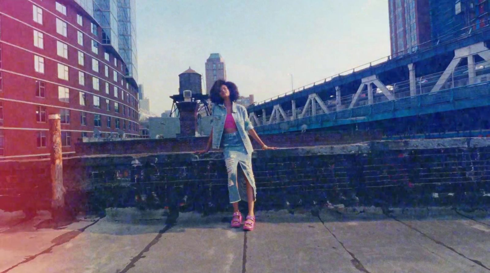 a woman riding a skateboard down a street next to tall buildings