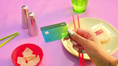 a person holding a credit card over a plate of food