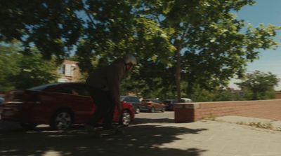 a man riding a skateboard next to a red car