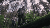 a man and a woman walking through a forest