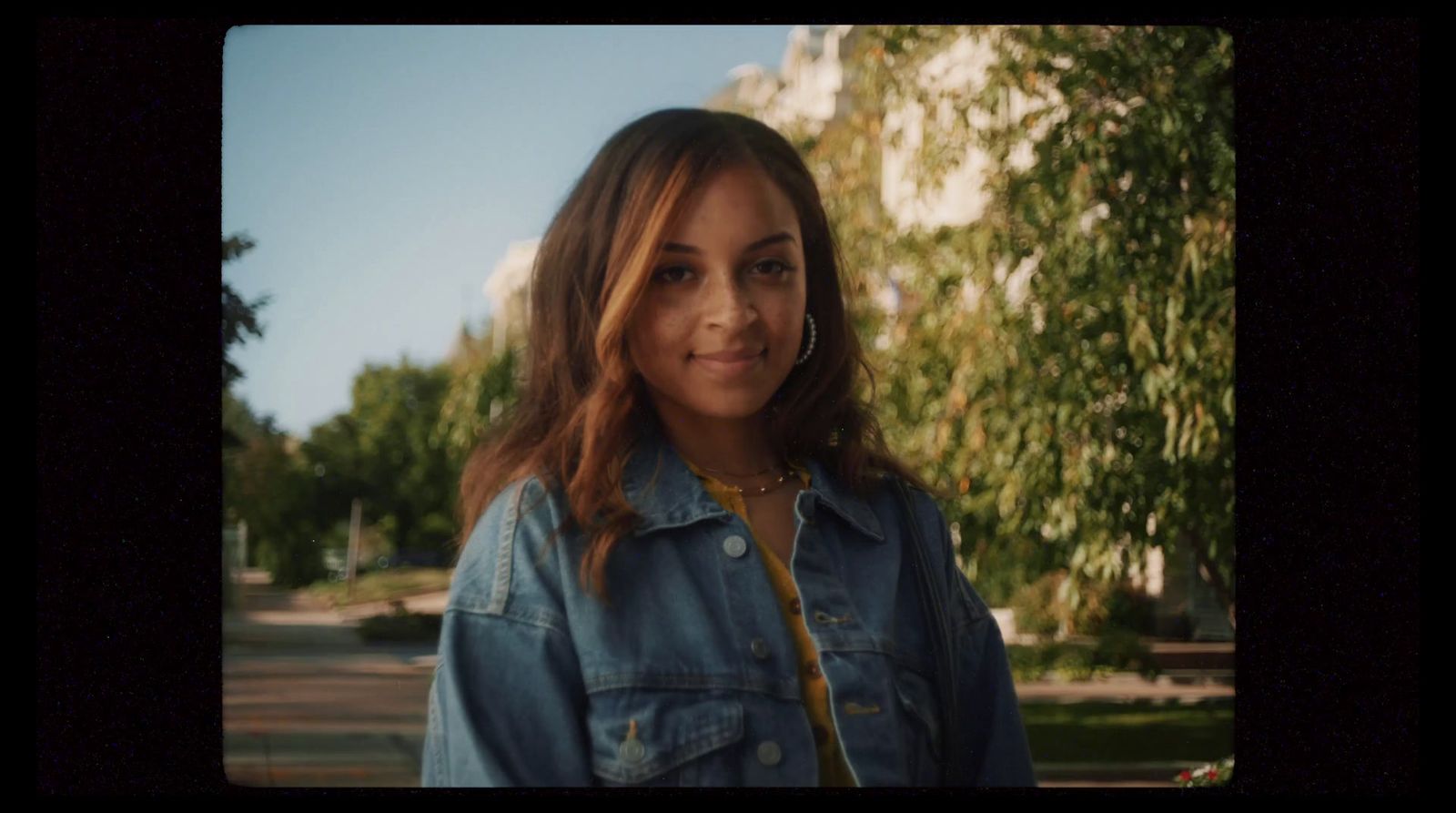 a woman wearing a jean jacket and a necklace