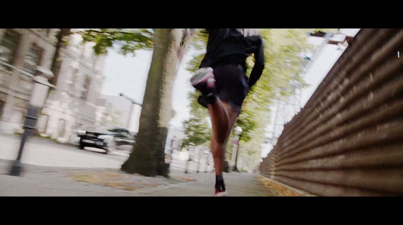 a woman running down a sidewalk next to a tree