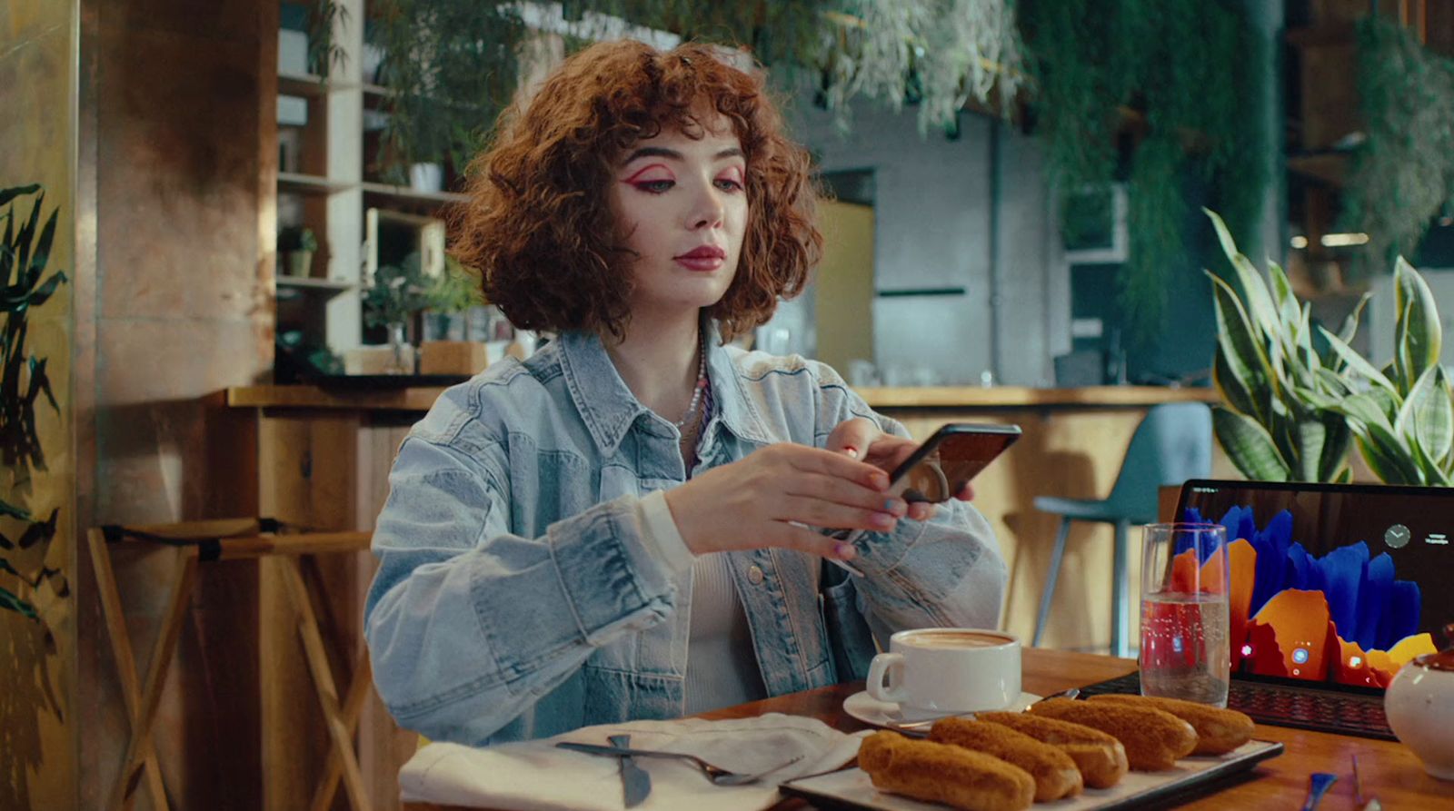 a woman sitting at a table looking at her cell phone