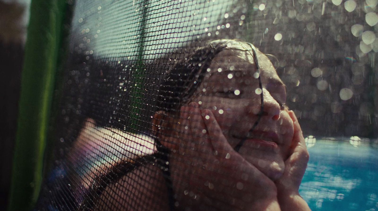 a woman looking through a screen at a pool