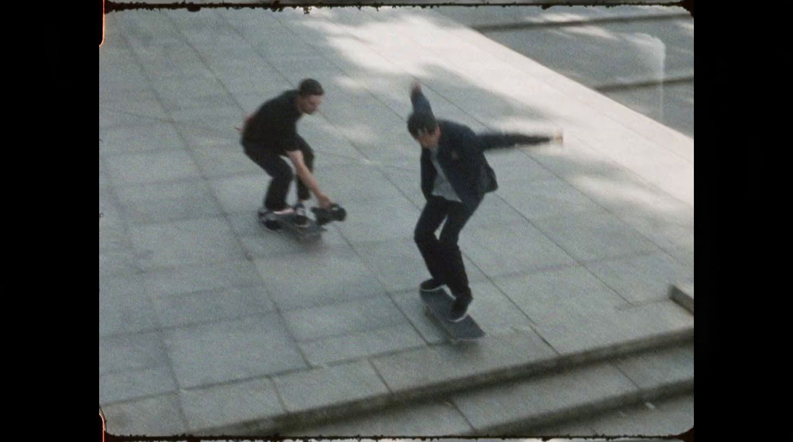 a couple of men riding skateboards down a sidewalk