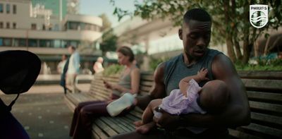 a man holding a baby while sitting on a bench