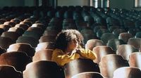 a little girl sitting in a row of empty chairs