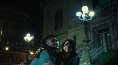 a man and a woman standing in front of a building at night