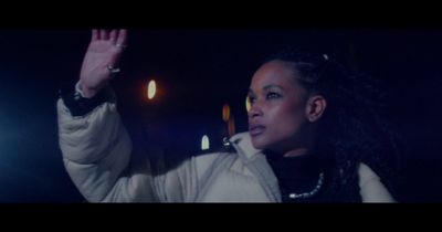 a woman with dreadlocks waves at the camera