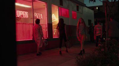 a group of people standing outside of a pizza shop