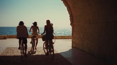 a group of people riding bikes next to the ocean