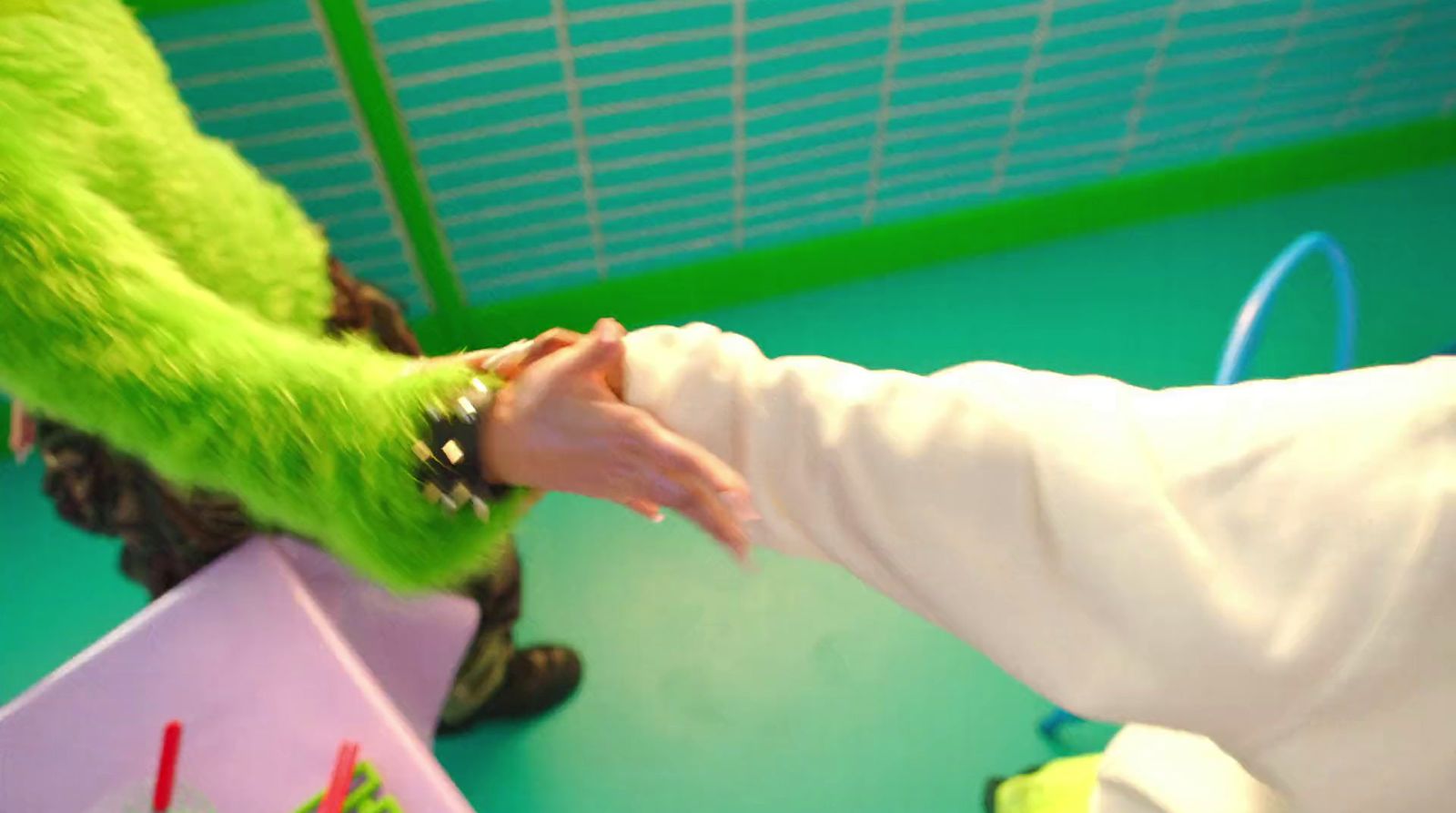 a person in a green furry animal costume touching another person's hand