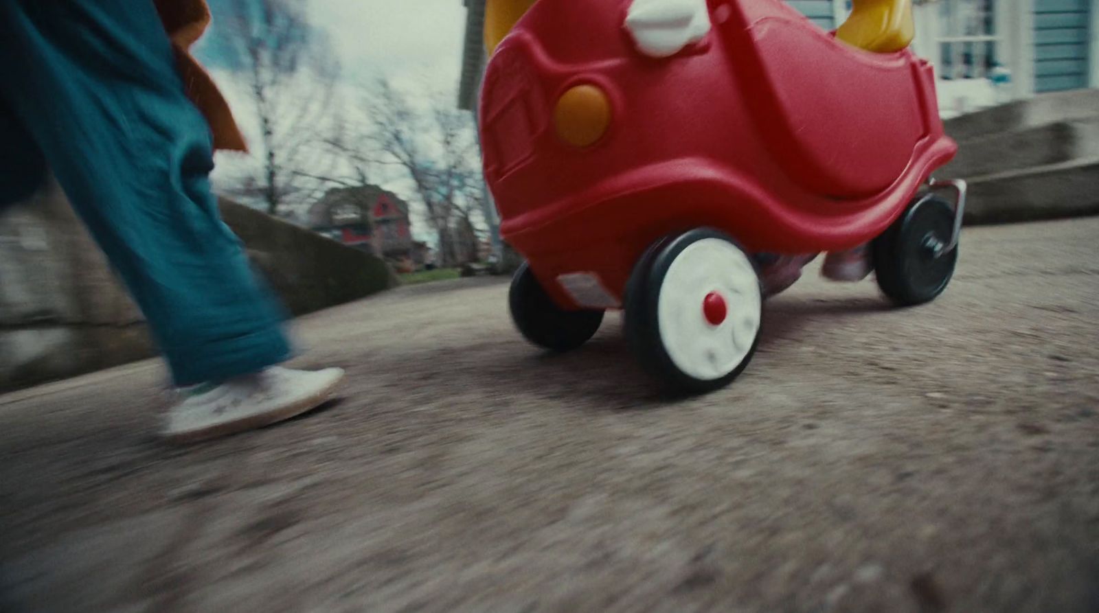 a child riding a toy car down a street