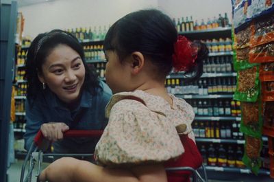 a woman pushing a shopping cart with a little girl on it