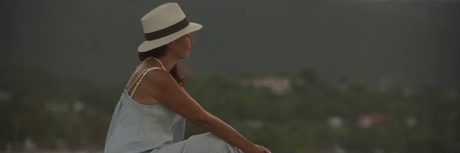 a woman wearing a hat sitting on a bench