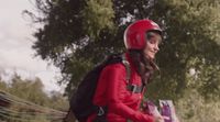 a woman in a red jacket and helmet riding a horse