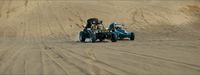 two people driving a buggy in the sand