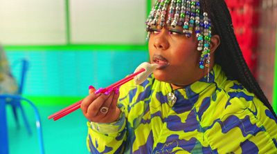 a woman with beads on her head brushing her teeth