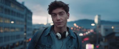 a man with headphones standing in front of a cityscape