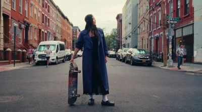 a woman holding a skateboard on a city street