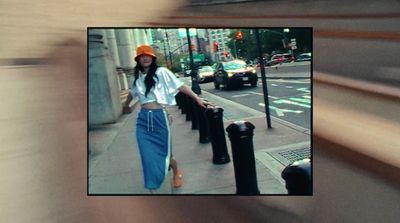 a woman walking down a street next to a tall building