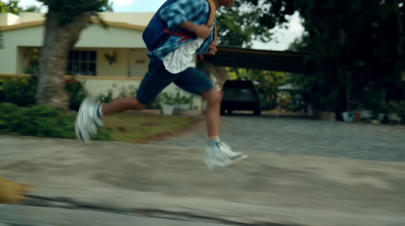 a man running down a street next to a house