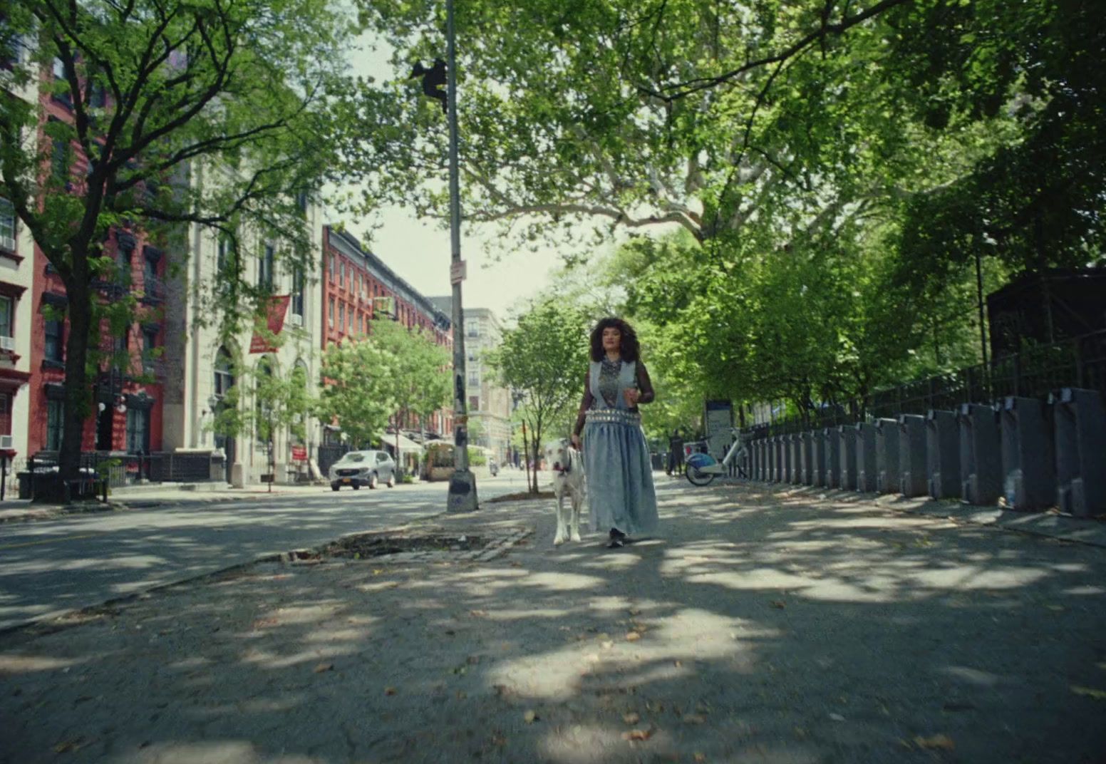 a woman walking down a street next to tall buildings