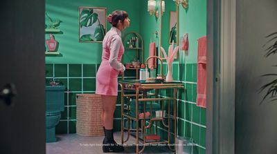 a woman standing in front of a green tiled bathroom