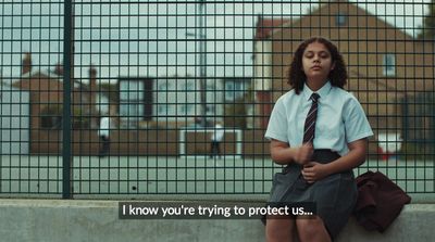 a girl in a school uniform sitting on a wall