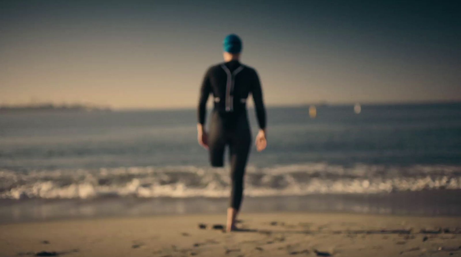 a man in a wet suit is walking on the beach