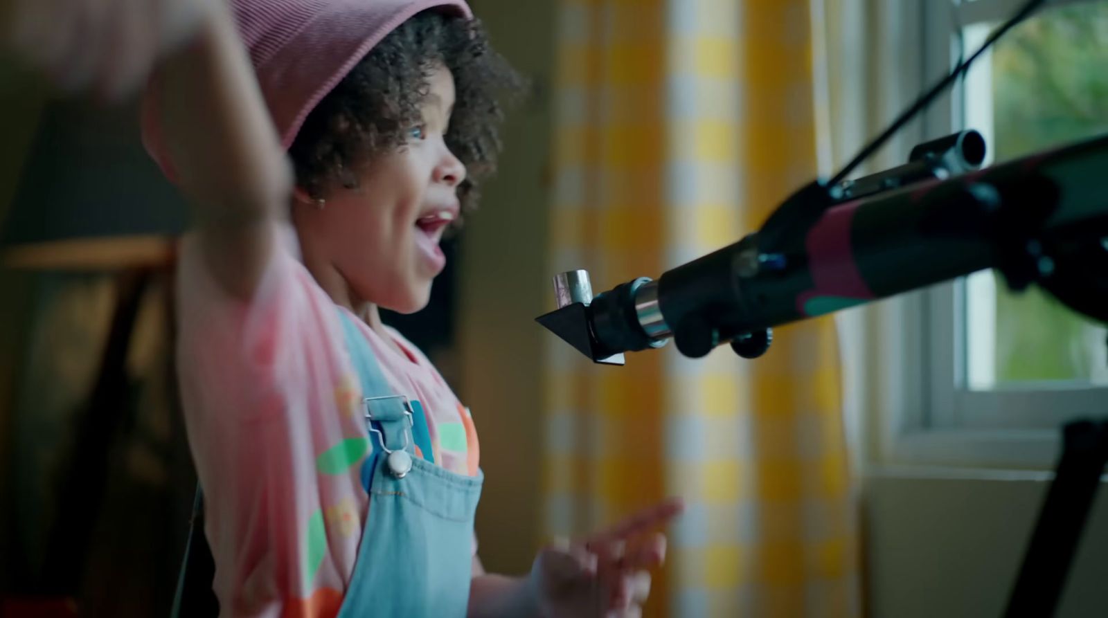 a little girl wearing a pink hat singing into a microphone