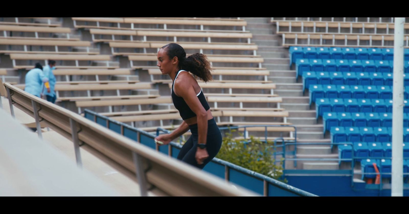 a woman in a black tank top and black leggings running on a track