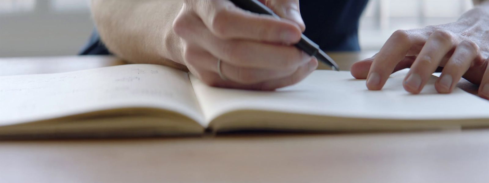 a person writing on a book with a pen