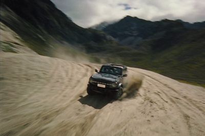 a black truck driving down a dirt road