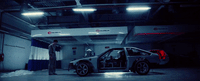 a man standing next to a car in a garage