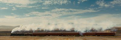 a train traveling through a rural countryside under a blue sky