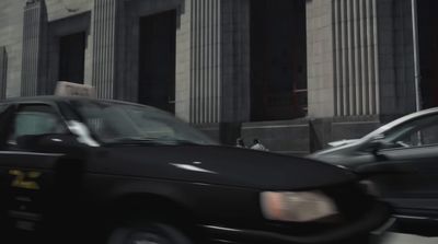 a black taxi cab driving down a street next to tall buildings