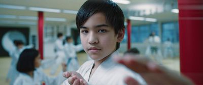 a young man in a karate pose with others in the background