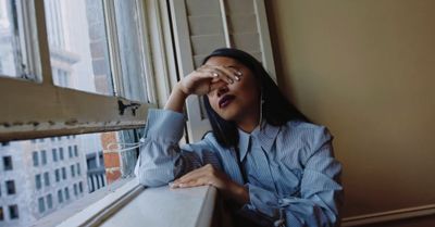 a woman looking out of a window with her hand on her face