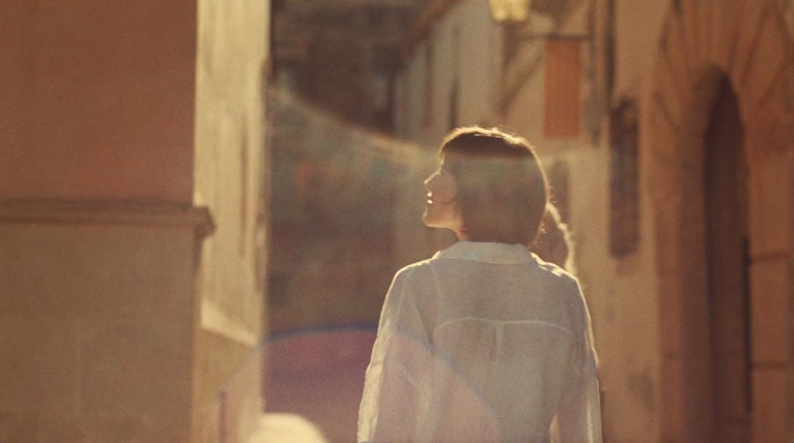 a woman walking down a street next to a building