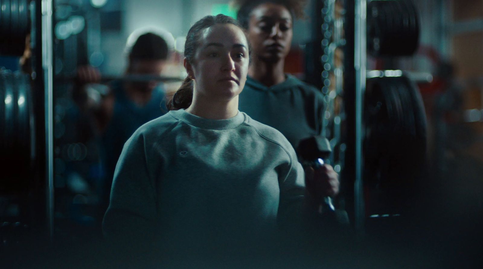 a woman standing in a gym holding a barbell