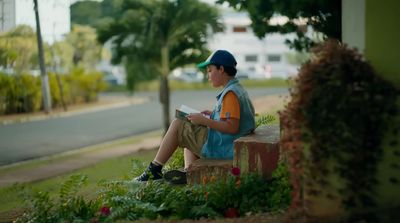 a boy sitting on a bench reading a book