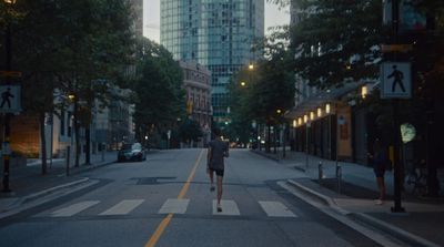 a man walking across a cross walk in a city