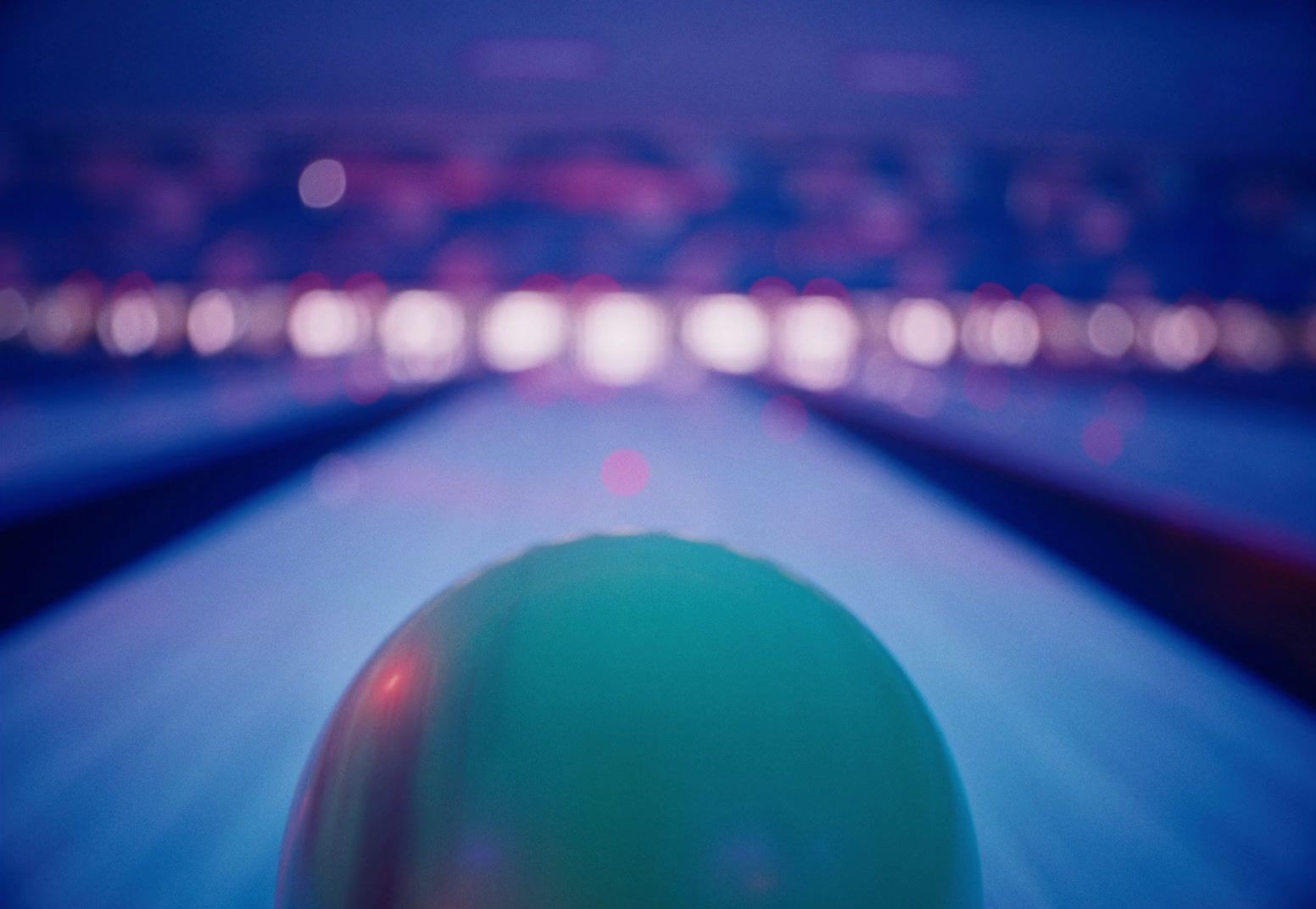 a green bowling ball sitting on top of a bowling alley