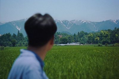 a man standing in a field looking at the mountains