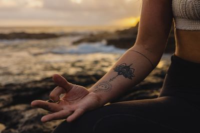 a woman sitting on a rock with a tattoo on her arm