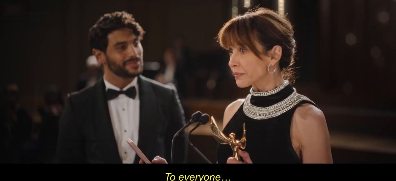 a man in a tuxedo standing next to a woman in a black dress