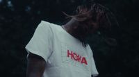 a man with dreadlocks standing in front of trees