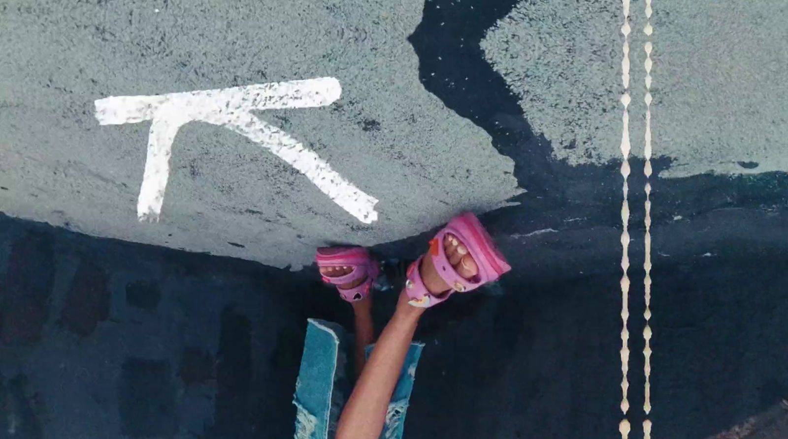 a person with pink shoes standing in the middle of a street